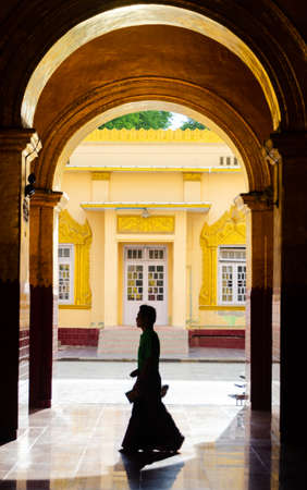 8 August 2012, Mandalay, Myanmar: Silhouette of a Burmese man wearing the traditional longyi (longskirt), inside the Mahamuni temple of Mandalay.のeditorial素材