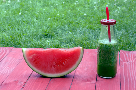 a slice of a watermelon and a fresh  smoothie in a bottleの写真素材