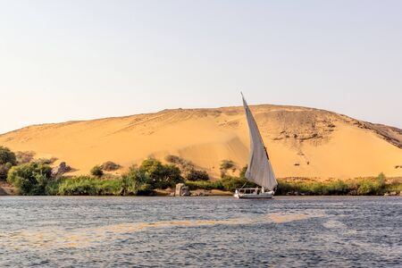horizontal view of a Nile scene with a boat in front of a dune, Egyptの写真素材
