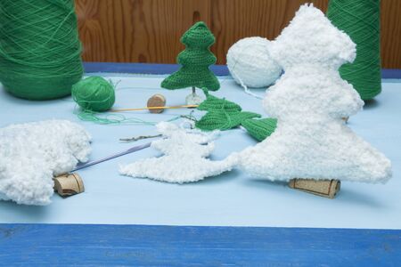 a horizontal frontal view of some handmade xmas decorations: white and green crochet trees and some of the materials neededの写真素材