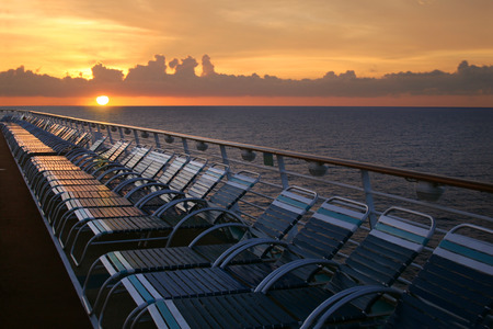 Looking over the deck of a cruise ship at sunset over the water