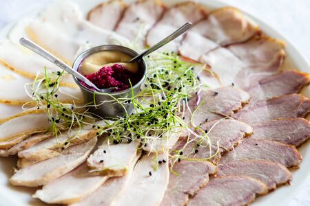 Meat, mustard, horseradish, greens on a plate. Slices of meat on a white plate.の写真素材