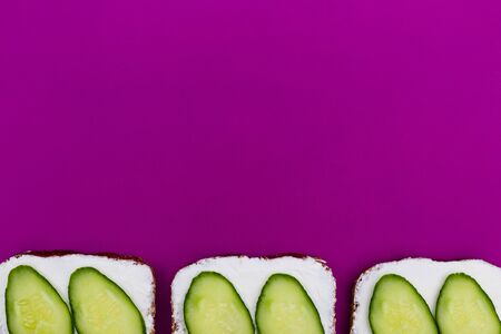 Sandwiches with soft cheese and cucumber - delicious healthy breakfast, snack. Flat lay with copy space on magenta background.の写真素材