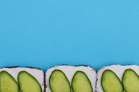 Sandwich with mayonnaise and cucumber on blue background with copy space. Concept of breakfast, toast, healthy food.の写真素材