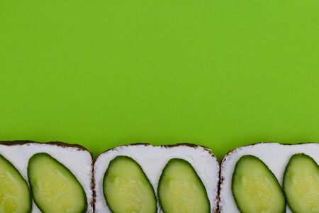 Summer sandwich with sauce and cucumber on green background. Sandwich top view, above, colorful background. Sandwich above with copy space.の写真素材