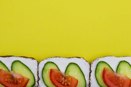 Sandwich with vegetables cucumber and tomato, yellow background with copy space. Concept of breakfast, toast, healthy food.の写真素材