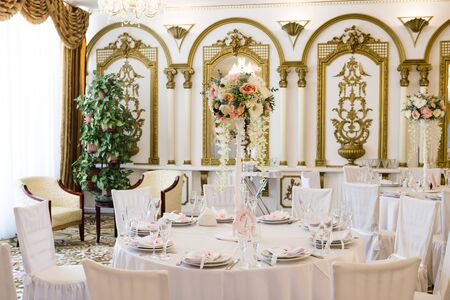 Wedding table for guests in restaurant decorated with flowers. White tablecloth, crystal glasses and cutlery, nobody.の写真素材