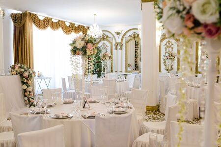Wedding table for guests in restaurant decorated with flowers. White tablecloth, crystal glasses and cutlery, nobody.の写真素材