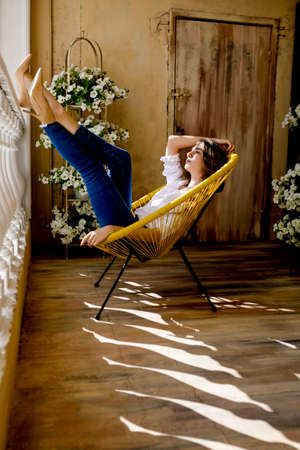 Young woman relaxing on her outdoor terrace. Young woman lying on chair, relaxing at home.の写真素材