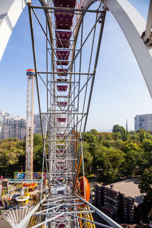 Metal construction of ferris wheel, green trees and city buildings on background. Vew from cabin, nobody.の写真素材