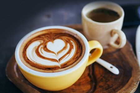 Cup of cappuccino with beautiful latte art on Wooden plate. Morning coffee for couple in love. Top view.の写真素材