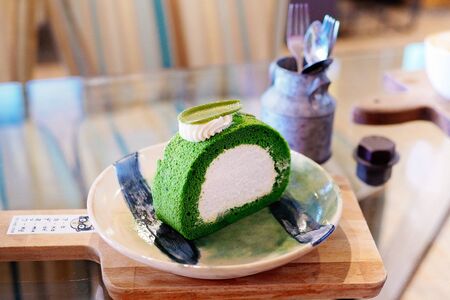 Cup of cappuccino with beautiful latte art on Wooden plate,Green tea roll jam on plate. Top view.の写真素材