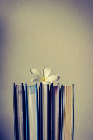 Stack of books and frangipani flower  on wooden table.の写真素材