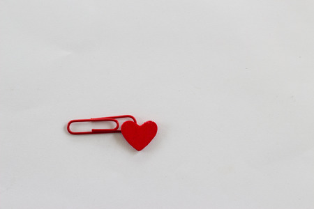 Heart-shaped wooden red. Red paper clip on a white background.
