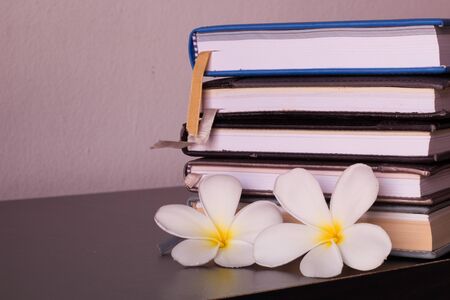 Stack of books and frangipani flower  on wooden table.の写真素材