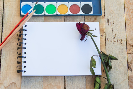 Painting equipments and  dry rose  on wood background.の写真素材