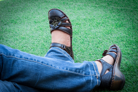 Women wearing dark brown shoes on the green grass. focus on shoesの写真素材