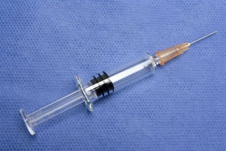 One small glass syringe in blue backgroundの写真素材