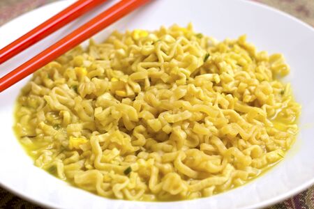 A dish of chicken noodles with red chopsticksの写真素材