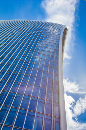 Low view on a skyscraper against the blue sky with curved lines