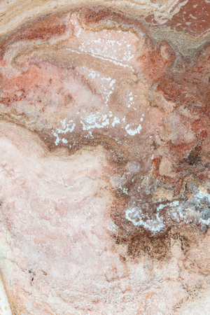 Pattern created by a high view on pink salines drying in the sun, forming curves of darker colors