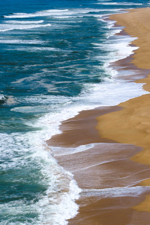 Aerial view of an empty beach during the summer in Nazare, portugal where the biggest waves are surfed during winter.の写真素材