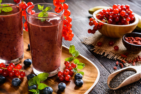 Fresh juicy smoothies with red currants, blueberry, banana, goji berries and chia seeds in a glass jarの写真素材