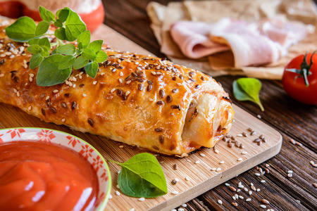 Savory strudel stuffed with ham, Feta cheese, tomato sauce and herbsの写真素材