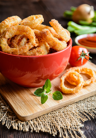 Deep - fried onion rings covered in breadcrumbs with ketchupの写真素材