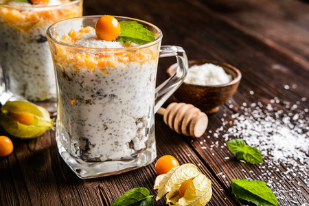 Probiotic yogurt with chia seeds, coconut, honey and physalis puree in a glass jarの写真素材