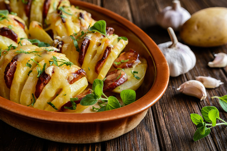 Baked potatoes stuffed with smoked sausage slices, cheese, garlic and herbsの写真素材