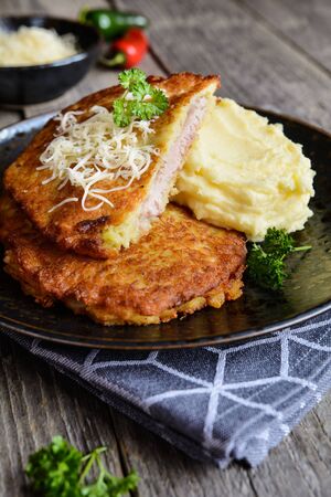 Fried pork cutlets coated in potato batter, studded with cheese and served with mashed potatoの写真素材