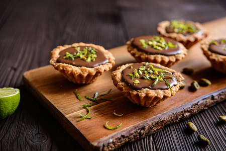 Tartlets with chocolate filling, pistachio and lime peel toppingの写真素材
