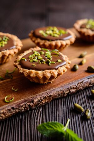 Tartlets with chocolate filling, pistachio and lime peel toppingの写真素材