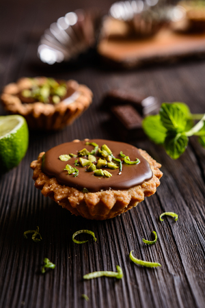 Tartlets with chocolate filling, pistachio and lime peel toppingの写真素材