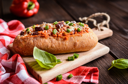 Baked baguette stuffed with mixture of minced pork, tomato sauce, beans, green bell pepper, onion, garlic and sprinkled with cheeseの写真素材