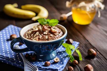 Raw oatmeal porridge with banana, hazelnut, chocolate and honeyの写真素材