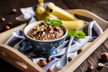 Raw oatmeal porridge with banana, hazelnut, chocolate and honeyの写真素材