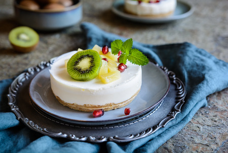 Delicious unbaked mini cheesecakes topped with pineapple, kiwi and pomegranateの写真素材