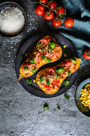 Roasted Butternut Squash stuffed with rice, bacon, broccoli, tomato, corn and cheeseの写真素材