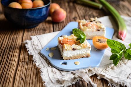 Delicious apricot cheesecake with rhubarb, topped with crumble and almond flakesの写真素材