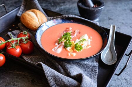 Salmorejo, cold tomato soup with Serrano ham and eggs in a ceramic bowl, served with pastryの写真素材
