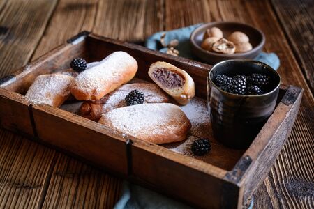 Sweet fried pastry with blackberry and walnut filling sprinkled with powdered sugar