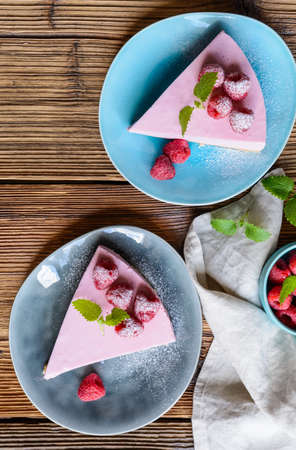 Refreshing no bake raspberry cheesecake topped with fresh berries, served on a ceramic plateの写真素材