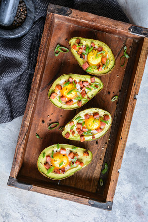 Roasted avocado egg boats with bacon and green onionの写真素材