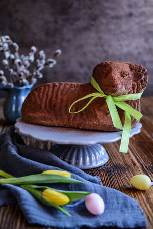 Classic chocolate Easter lamb pound cake sprinkled with cocoa powder on wooden background