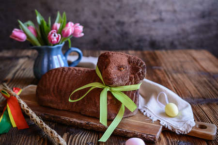 Classic chocolate Easter lamb pound cake sprinkled with cocoa powder on wooden background