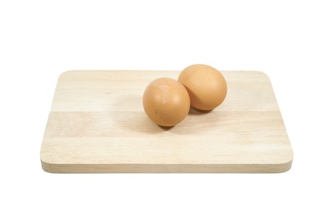2 eggs on a wooden cutting board, white background.