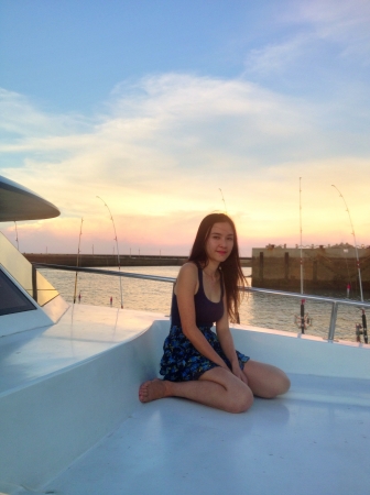 Girl sitting on a boat, against sunsetの素材