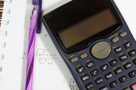 Maths concept - handheld calculator on a sheet of paper with maths-formulas